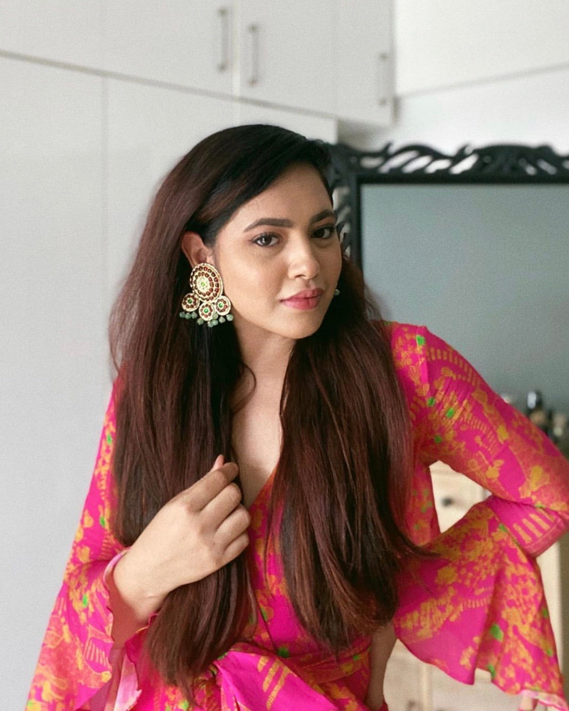Fashion influencer wearing Abharika earrings with bright pink and gold traditional Indian outfit, showcasing temple jewelry styling - Aaharya