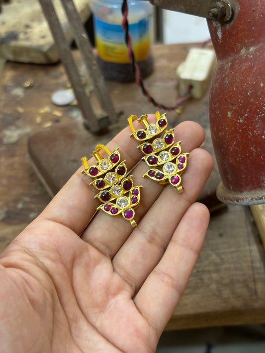 A hand holding finished gilded pieces at the workbench