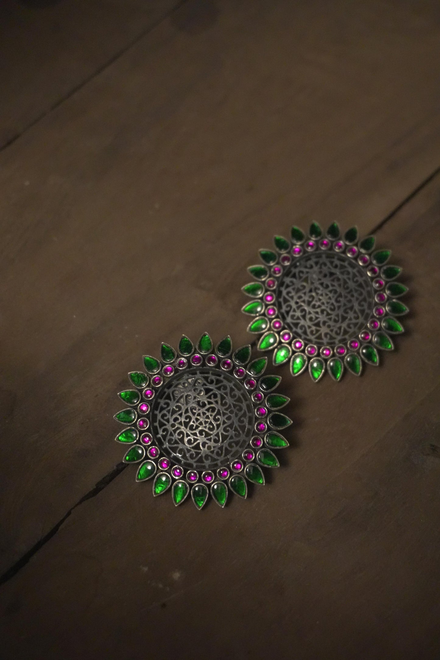 Round tribal silver jewellery earrings with intricate 92.5 silver filigree, accented with green and pink enamel petals.