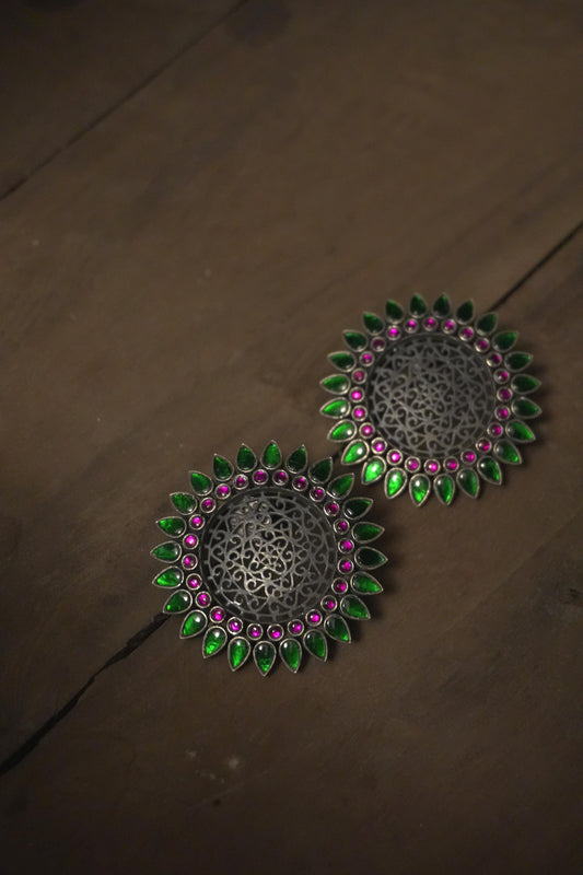 Round tribal silver jewellery earrings with intricate 92.5 silver filigree, accented with green and pink enamel petals.