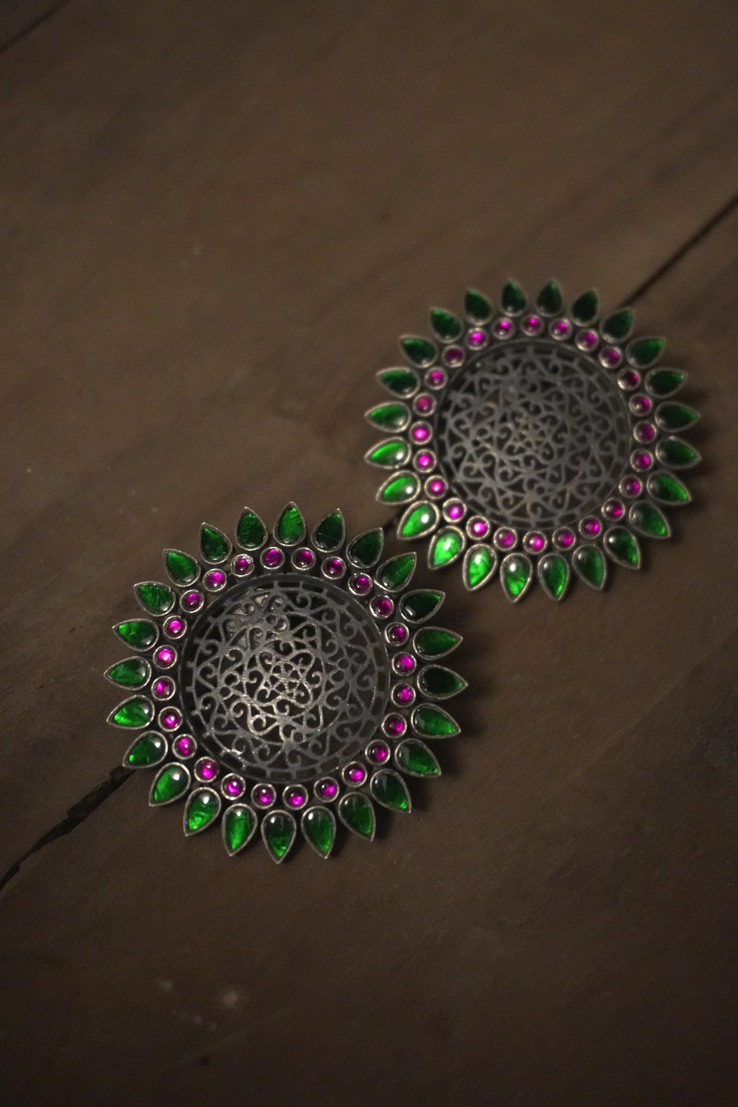 Round tribal silver jewellery earrings with intricate 92.5 silver filigree, surrounded by green and pink stones.