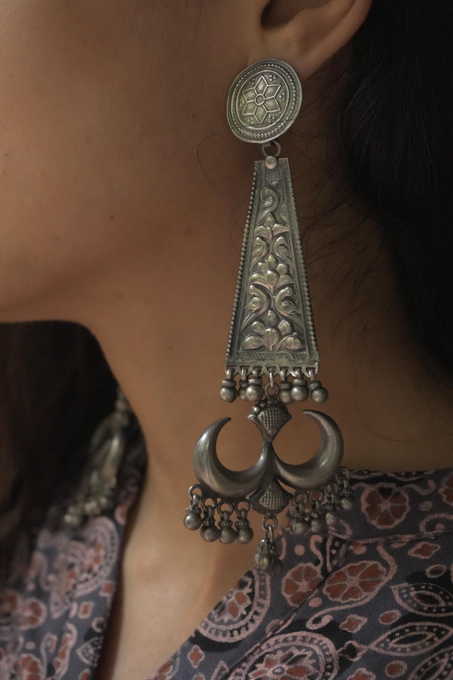 Tribal silver jewellery Ravya earrings in 92.5 silver with intricate floral and crescent moon design.