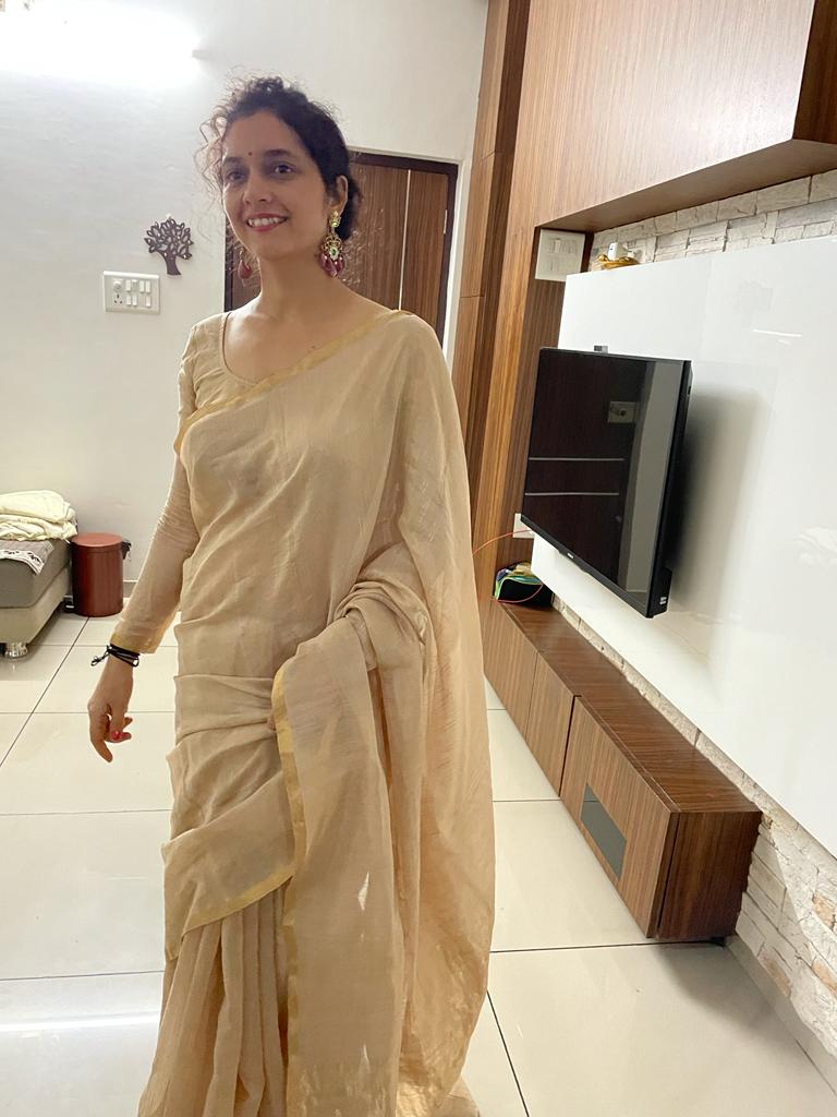 Woman wearing Abharika temple earrings with simple beige saree in modern home setting - casual traditional styling