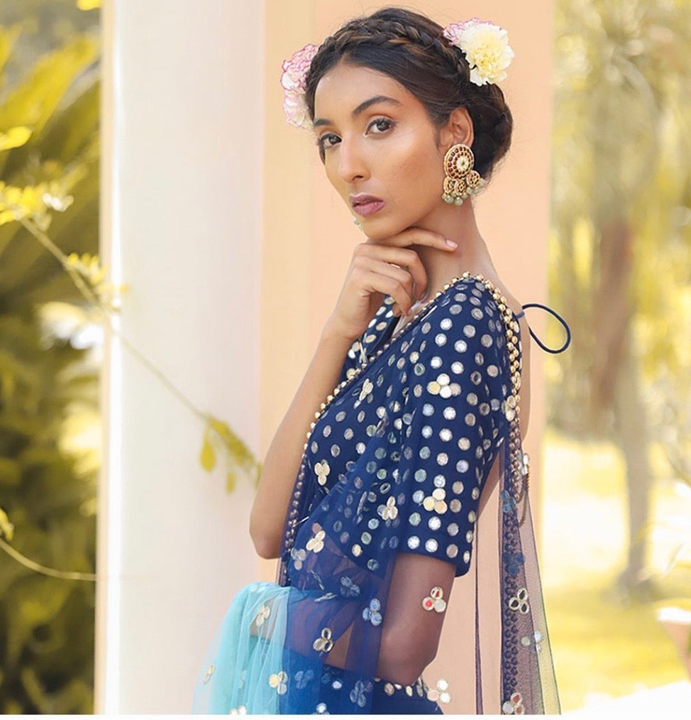 Model wearing Abharika statement studs with blue and gold polka dot saree blouse, flower in hair, showcasing elegant traditional Indian styling - Aaharya temple jewelry