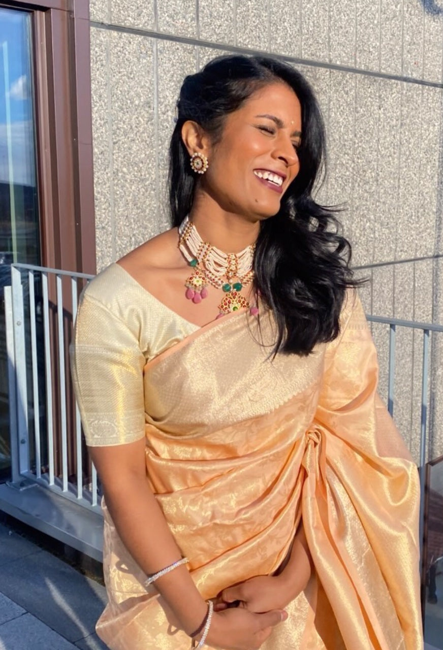Woman in golden silk saree wearing Abharika temple necklace with colorful gemstones and matching earrings by Aaharya